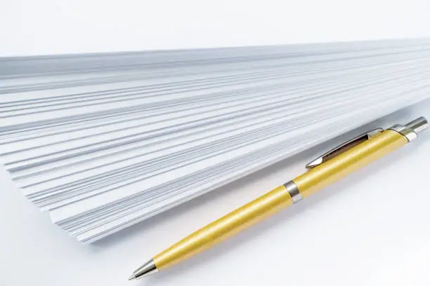 Photo of gold ball point pen lying on the pile of paper for those who write