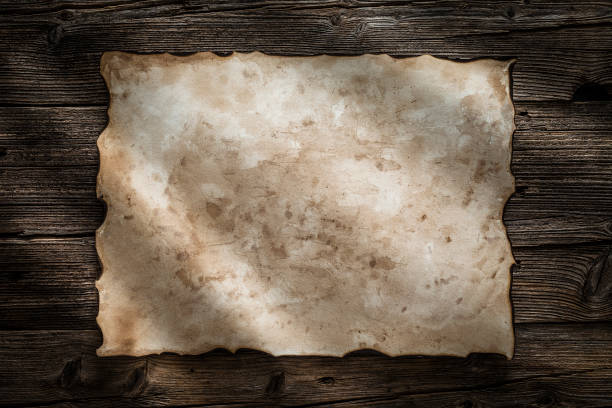istock Old burnt parchment posted to a wood background 1162588922