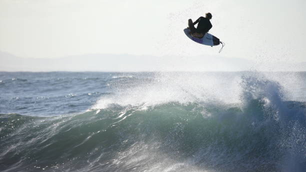 Boost! A young surfer flys through the air doing a massive grab it Main Beach, Byron Bay