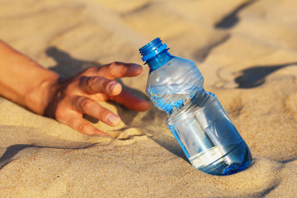 istock Hand on the sand reaches for a bottle of drinking water. Thirst concept 1162598332