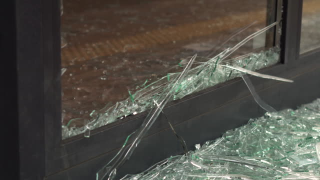 Window frame with broken glass close-up. Small pieces of broken glass from the window. Vandalism threatens private property. Insurance, security systems and video surveillance to protect property