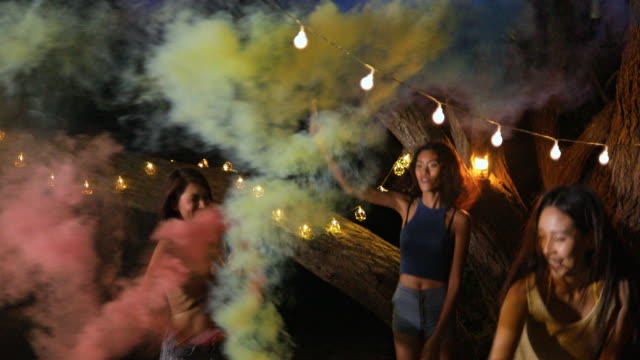 The Asian teen girl playing sparklers and smoke colors and have fun on the beach with beautiful sea in Thailand.