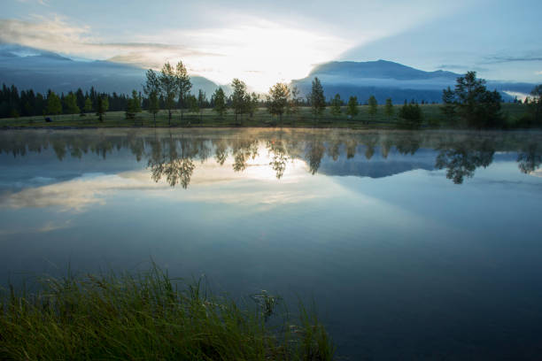 reflejo perfecto del bosque y las montañas en el lago al amanecer - rocky mountains exploration horizontal outdoors fotografías e imágenes de stock