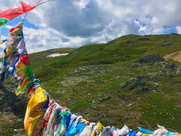 Buddhist prayer flags in the Sayan mountains Colorful Buddhist Tibetan prayer flags with mantras waving in the wind at the Sayan mountain pass in the Tyva Republic on a summer day siberian flag stock pictures, royalty-free photos & images