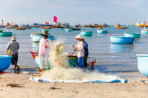 Mui Ne, Vietnam - FEBRUARY 22, 2018: Fishers lay down fishing nets in a fishers harbor in Mui Ne, Vietnam