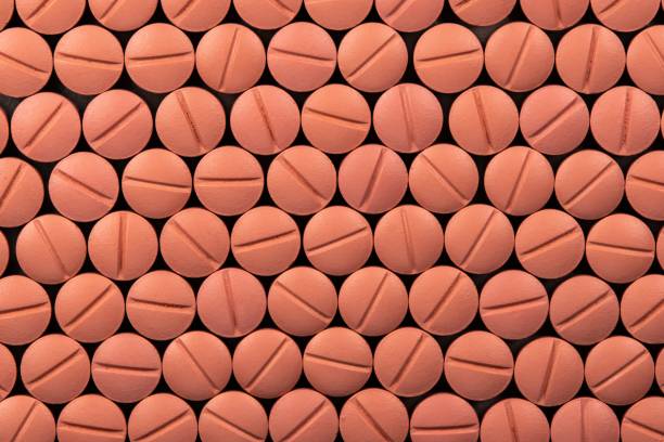 istock Orange colour round pills on black  background with selective focus. Pills that look like ecstasy 1162610645