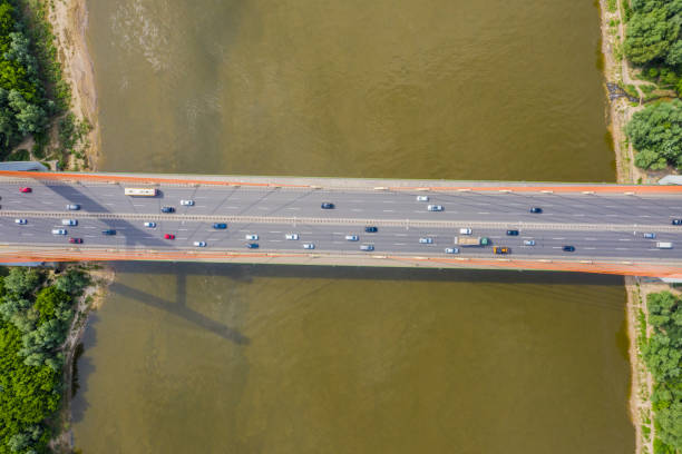 istock City car moving at highway bridge on background smooth river surface drone view. Aerial view 1162614667