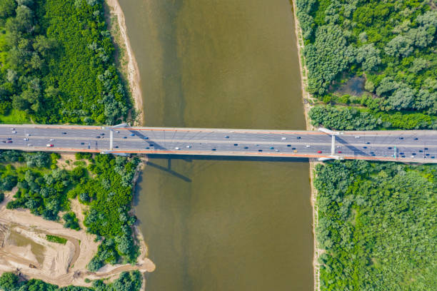 istock City car moving at highway bridge on background smooth river surface drone view. Aerial view 1162614678
