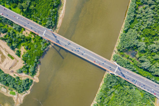 istock City car moving at highway bridge on background smooth river surface drone view. Aerial view 1162614687