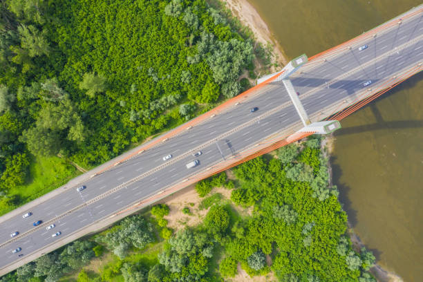 istock City car moving at highway bridge on background smooth river surface drone view. Aerial view 1162614765
