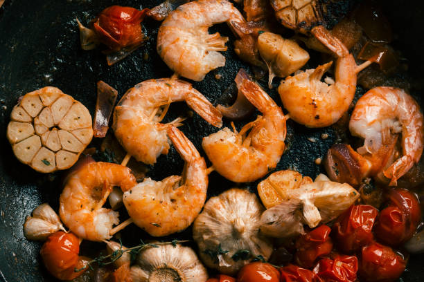 istock Black frying pan with prawns and vegetables on it 1162614900