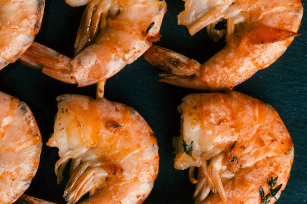 istock Roasted shrimps on skewers placed on black background 1162614919