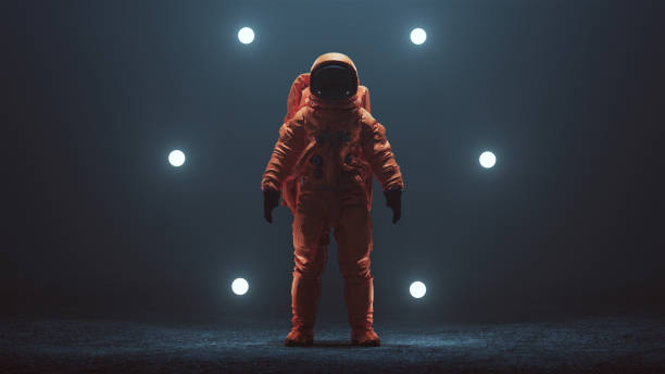 istock Astronaut in an Orange Space Suit with Black Visor Standing in a Alien Void 1162618048