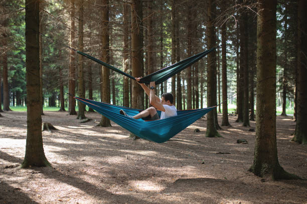 istock Young man trying to find a comfortable position to sleep in a hammock 1162618224