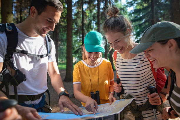 istock Joyful group of hikers looking at the map and joking around 1162618225