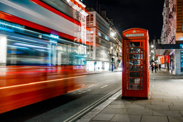 Light trails of a double decker bus next to the iconic telephone booth in London