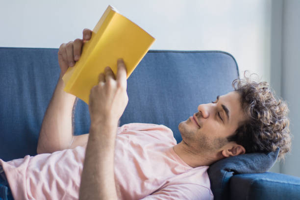 istock Man relaxed and reading a book on sofa 1162621627
