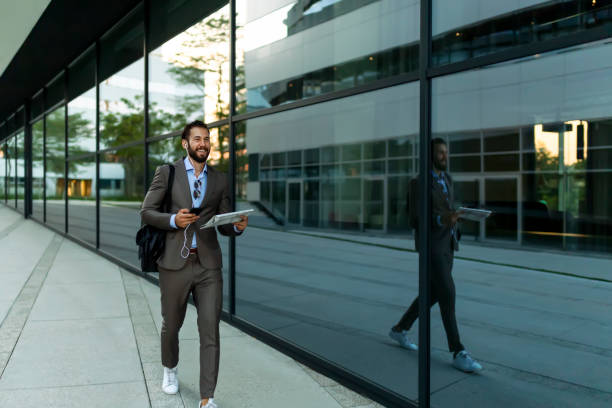 Reading the Latest News Reading the Latest News. Confident Young Man in Full Suit Reading Newspaper While Walking Outdoors With Cityscape in the Background. Image of a Mid Adult Handsome Businessman Outdoors at the Street Near Business Center Reading Newspaper newspaper airport reading business person stock pictures, royalty-free photos & images