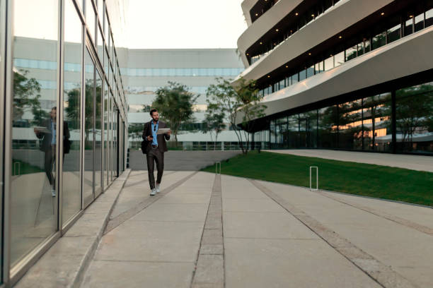 Reading the Latest News Reading the Latest News. Confident Young Man in Full Suit Reading Newspaper While Walking Outdoors With Cityscape in the Background. Image of a Mid Adult Handsome Businessman Outdoors at the Street Near Business Center Reading Newspaper newspaper airport reading business person stock pictures, royalty-free photos & images