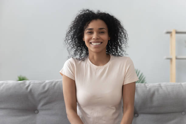 istock Smiling young african woman sit on sofa looking at camera 1162624124
