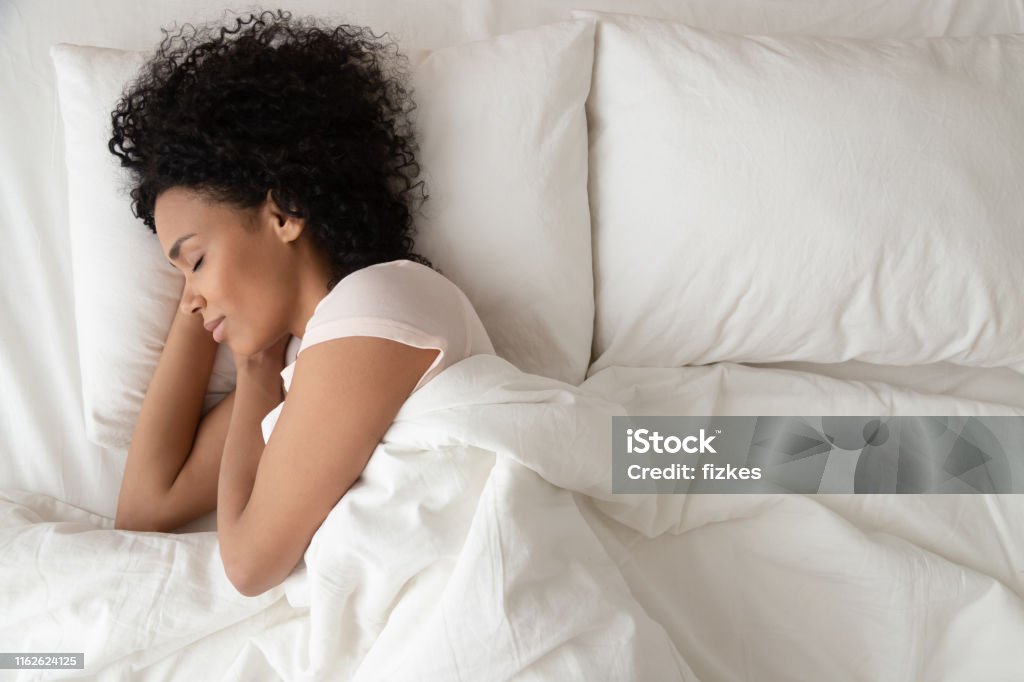 Serena calma mujer africana durmiendo en la cama cómoda, vista superior - Foto de stock de Dormir libre de derechos