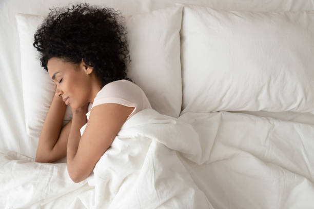 serene calm african woman sleeping in comfortable bed, top view - woman sleeping imagens e fotografias de stock