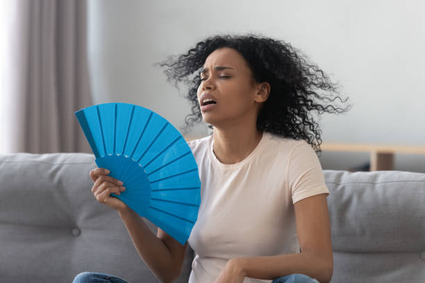 Overheated african young woman feeling hot waving fan at home Overheated african young woman feeling hot waving fan annoyed with high temperature sit on sofa at home, stressed black girl sweating suffer from summer weather heat problem without air conditioner hyperthermia photos stock pictures, royalty-free photos & images
