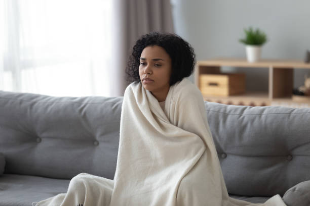 Sick african woman feeling cold covered with blanket at home Sick young african woman feeling cold covered with blanket sit on sofa, ill black girl shivering freezing warming at home wrapped with plaid, no central heating problem, fever temperature flu concept shivering stock pictures, royalty-free photos & images