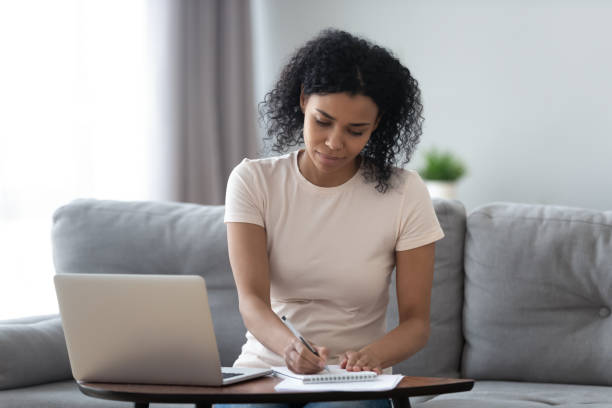 istock Focused african girl student study online at home making notes 1162624139
