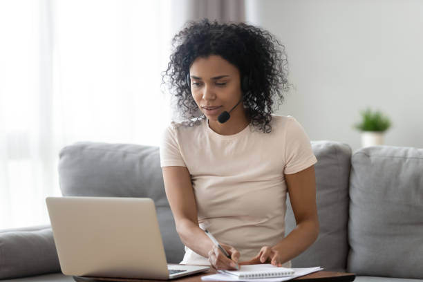 istock Young african woman wearing headset looking at laptop making notes 1162624149