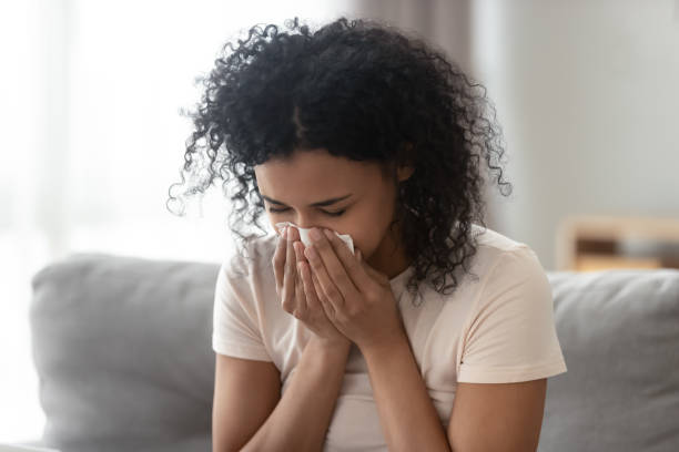 ill allergic african woman blowing nose in tissue at home - russian influenza epidemic virus flu virus imagens e fotografias de stock