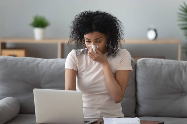 allergic african woman blowing nose in napkin sit at home - russian influenza epidemic virus flu virus imagens e fotografias de stock