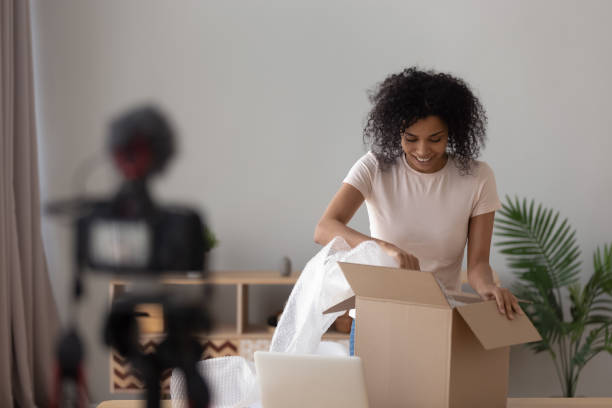 Happy african young woman blogger open parcel shooting vlog