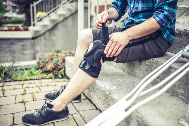 istock man sitting on the steps and adjusting his orthosis after having knee sprain 1162624238
