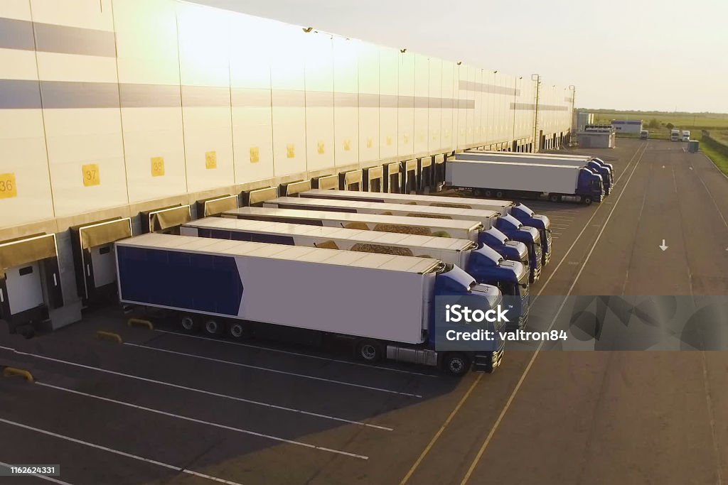 Distributionslager mit Lastwagen, die auf die Verladung warten - Lizenzfrei Lagerhalle Stock-Foto