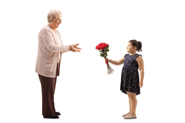 little girl giving a bunch of red roses to a grandmother - grandmother giving gift child imagens e fotografias de stock