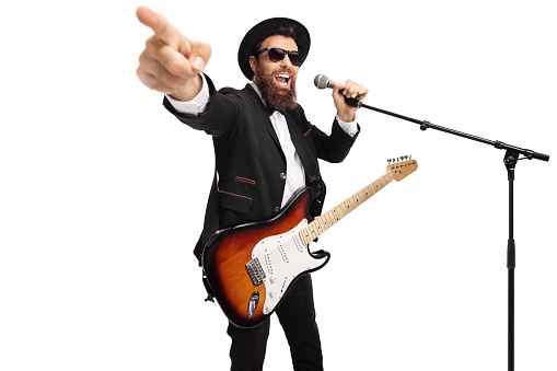 Man with an electric guitar singing on a microphone and pointing isolated on white background
