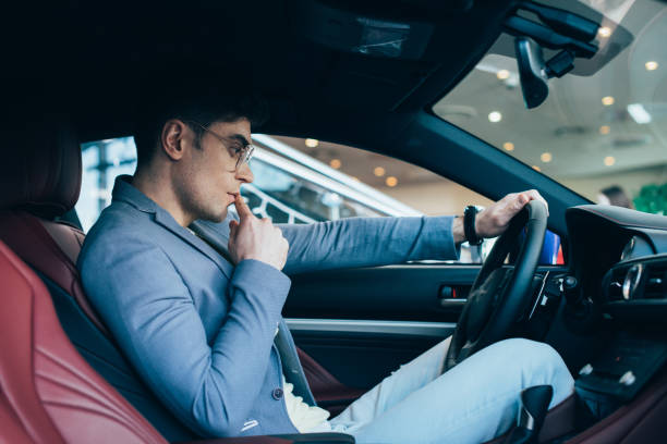 istock pensive stylish man in glasses thinking while holding steering wheel in automobile 1162627746