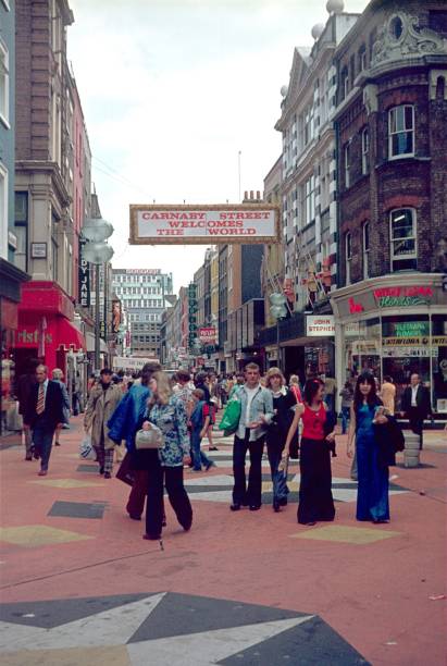 London, England, UK, 1976. Carnaby Street with visitors, shoppers, advertising signs, shops and buildings in London.