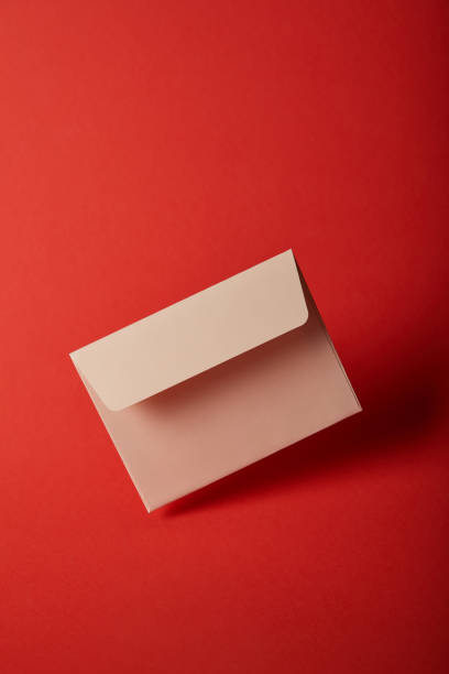 istock beige, blank and empty envelope on bright colorful red background with copy space 1162633024