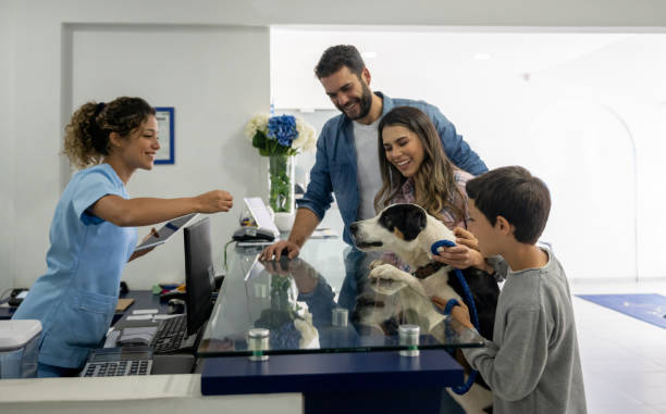 Happy family taking their dog to the vet Happy Latin American family taking their dog to the vet and it getting a treat from the receptionist animal hospital stock pictures, royalty-free photos & images