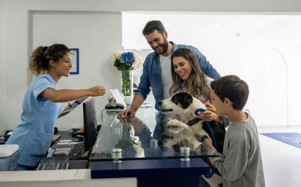 Happy family taking their dog to the vet Happy Latin American family taking their dog to the vet and it getting a treat from the receptionist veterinary surgery stock pictures, royalty-free photos & images