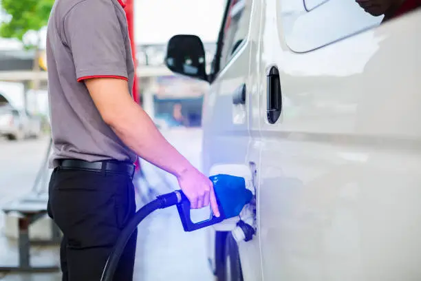 Photo of Hand refilling the white van with fuel at the gas station.