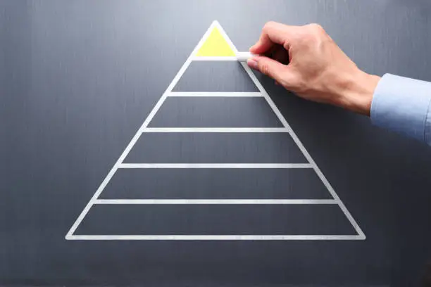 Businessman drawing pyramid on chalkboard.