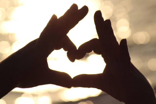 istock Male hands in a heart shape at sunset on the beach 1162643602