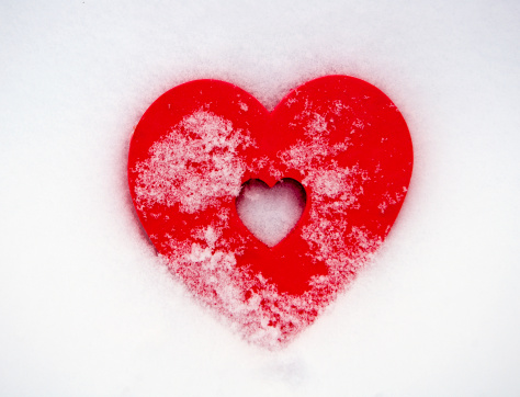 A red heart in fresh fallen snow with copy space.
