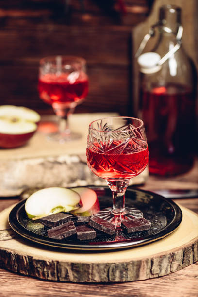 Glass of homemade redcurrant nalewka with apple slices and chocolate Glass of homemade redcurrant nalewka with apple slices and chocolate on metal plate nalewka stock pictures, royalty-free photos & images