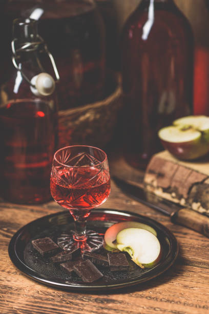 Glass of homemade redcurrant nalewka with apple slices and chocolate Glass of homemade redcurrant nalewka with apple slices and chocolate on metal plate nalewka stock pictures, royalty-free photos & images