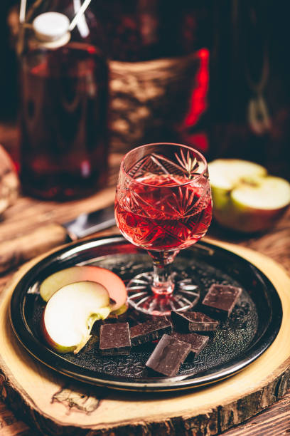 Glass of homemade currant nalewka and chocolate with apple Glass of homemade currant nalewka and chocolate with sliced apple on metal tray nalewka stock pictures, royalty-free photos & images