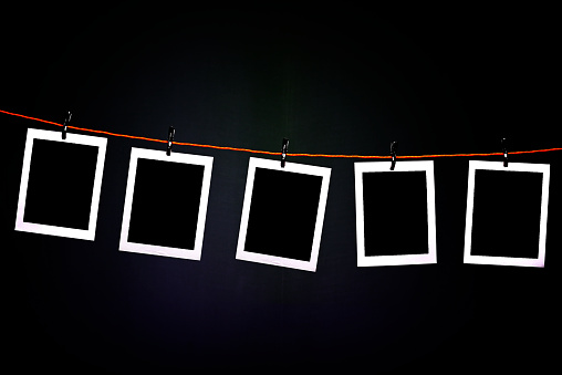 Blank polaroid photographs hanging on a rope in photography dark room